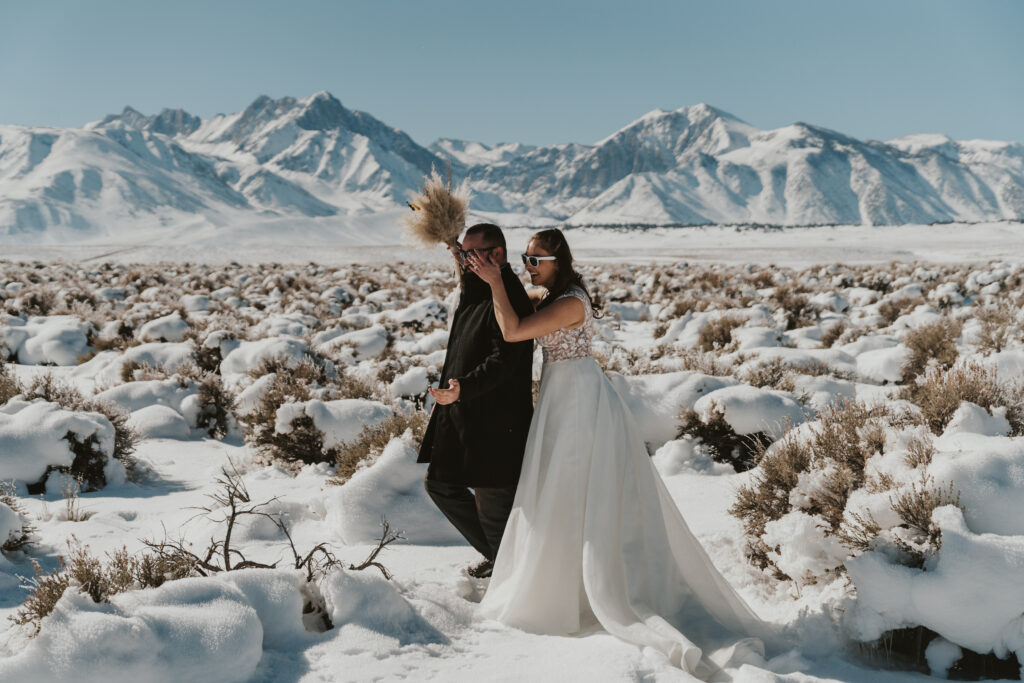 Winter elopement in mammoth lakes first look photo of bride sneaking up behind groom
