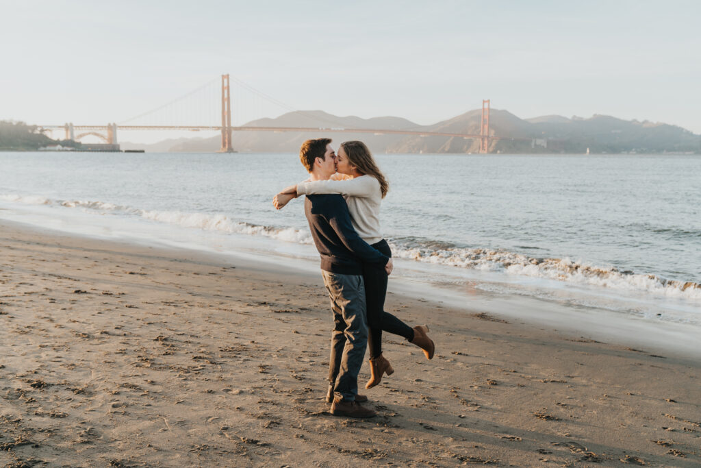 San Francisco engagement photos on the beach in front of Golden Gate Bridge couple kissing in front of Ocean