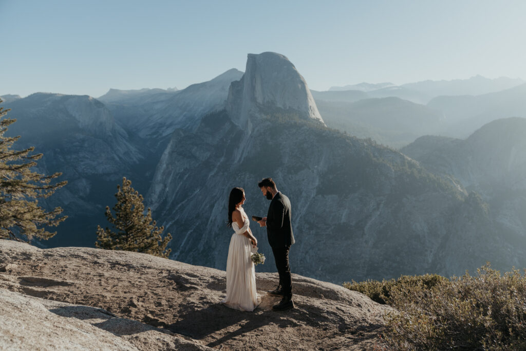 Bride and groom exchanging vows at Glacier Point for their Yosemite elopement ceremony in front of Half Dome