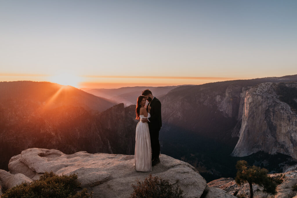 Bride and groom standing on Taft Point after their elopement in Yosemite National Park during sunset with El Capitan in the background