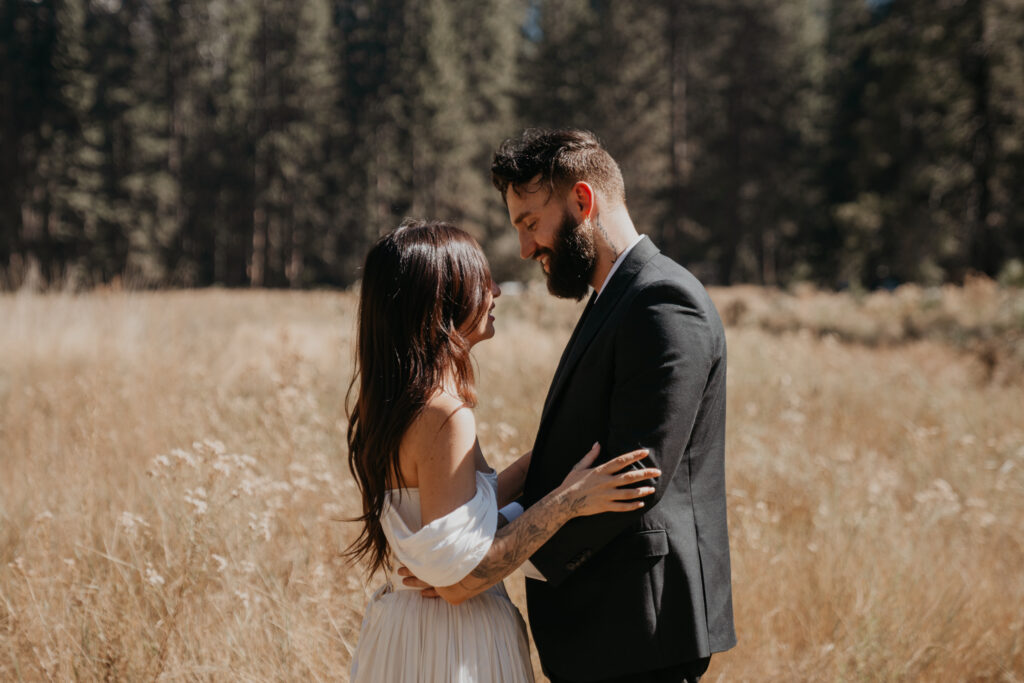 Bride and groom looking at eat other standing in a meadow in Yosemite