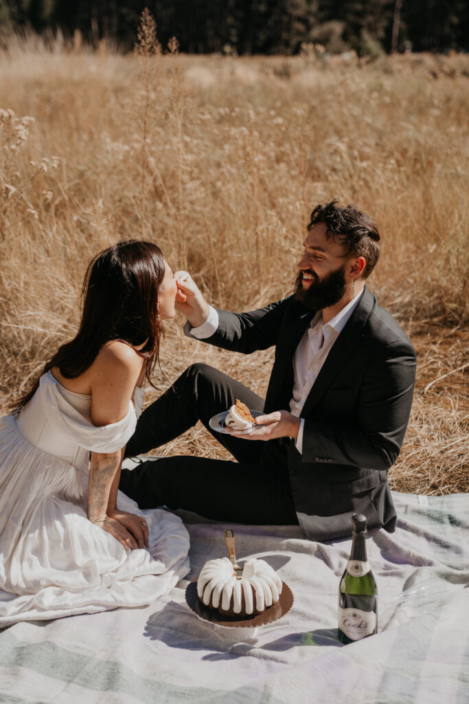 Groom feeds cake to his bride after cake cutting at their Yosemite elopement